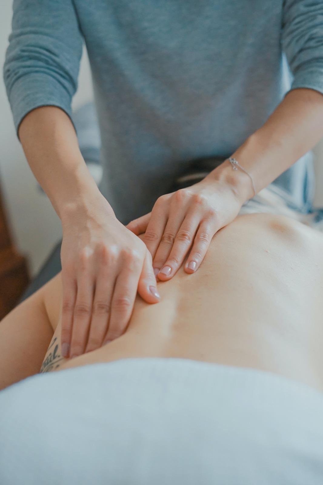 Hands working along a client’s back during a massage